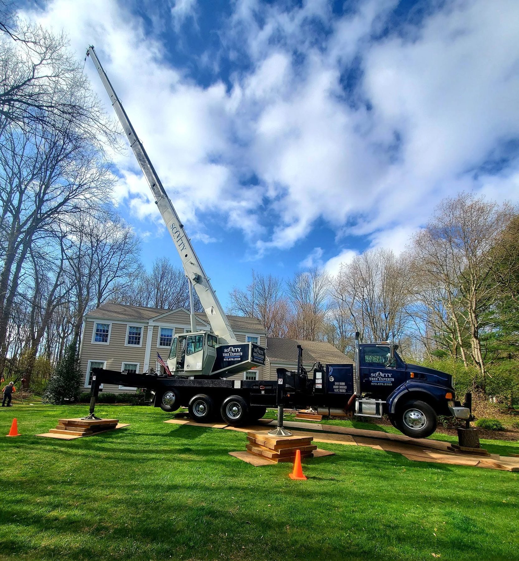 Scotty Tree Experts crane truck set up on a residential lawn