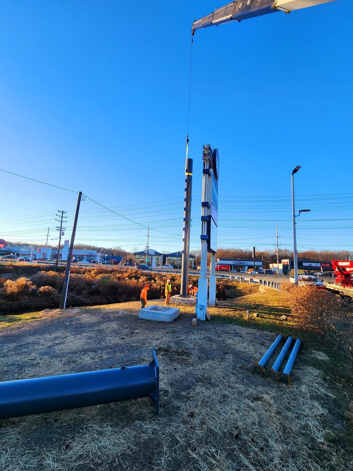 Crane positioning a support post for a large roadside sign
